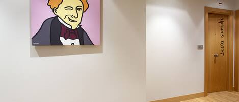 A hallway with a wooden floor, a door labeled "Jesus Guridi," and a framed portrait on the wall.