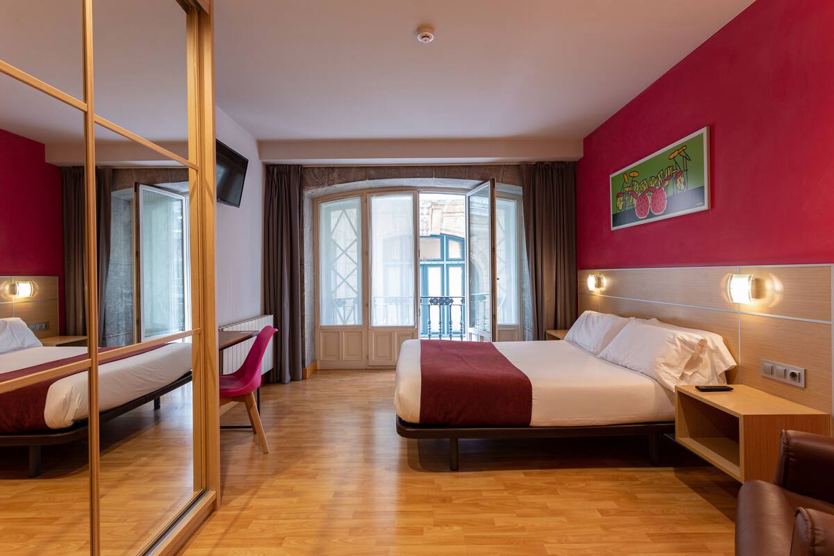 Habitación de hotel con dos camas, un espejo, un escritorio y una silla.