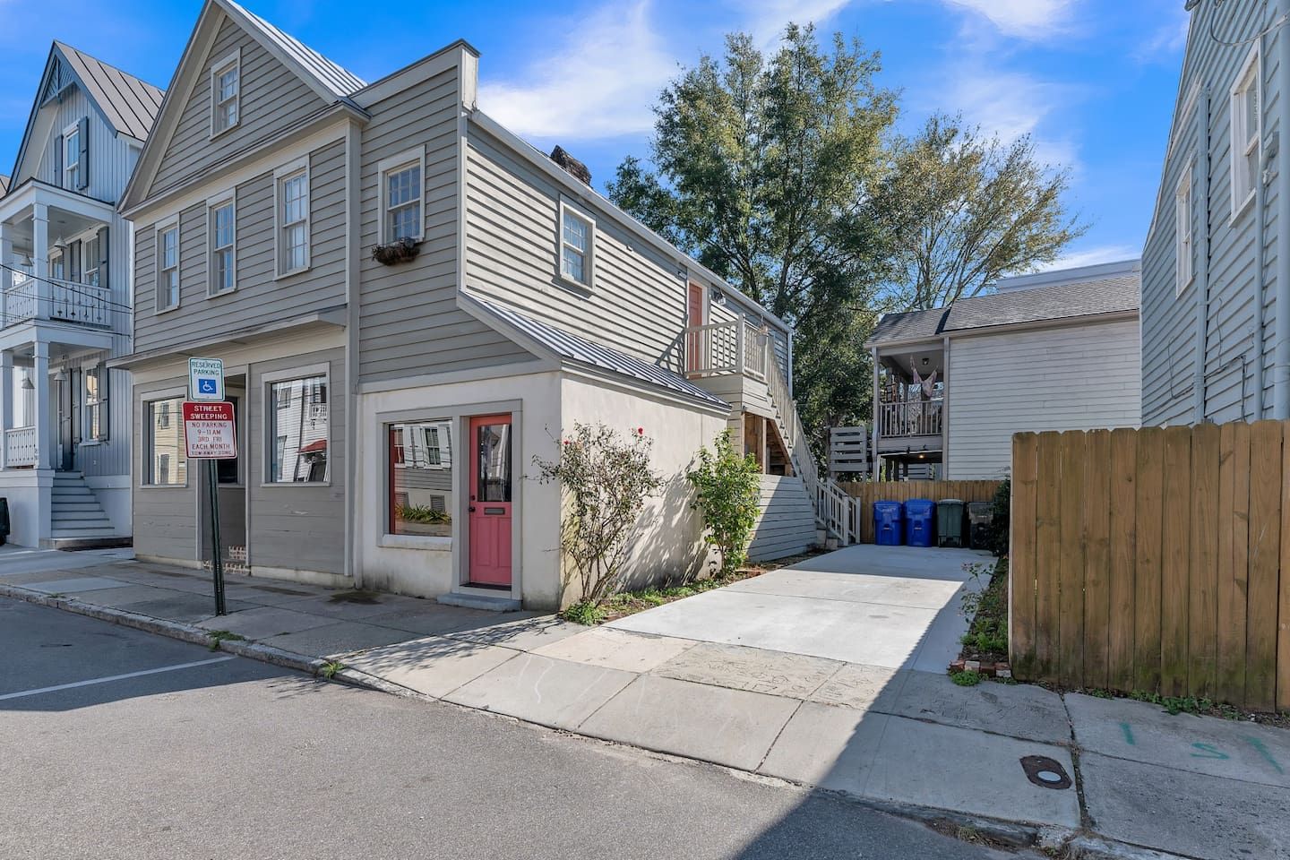 A residential building with a red door, a visible garage, and a street sign indicating parking regulations.