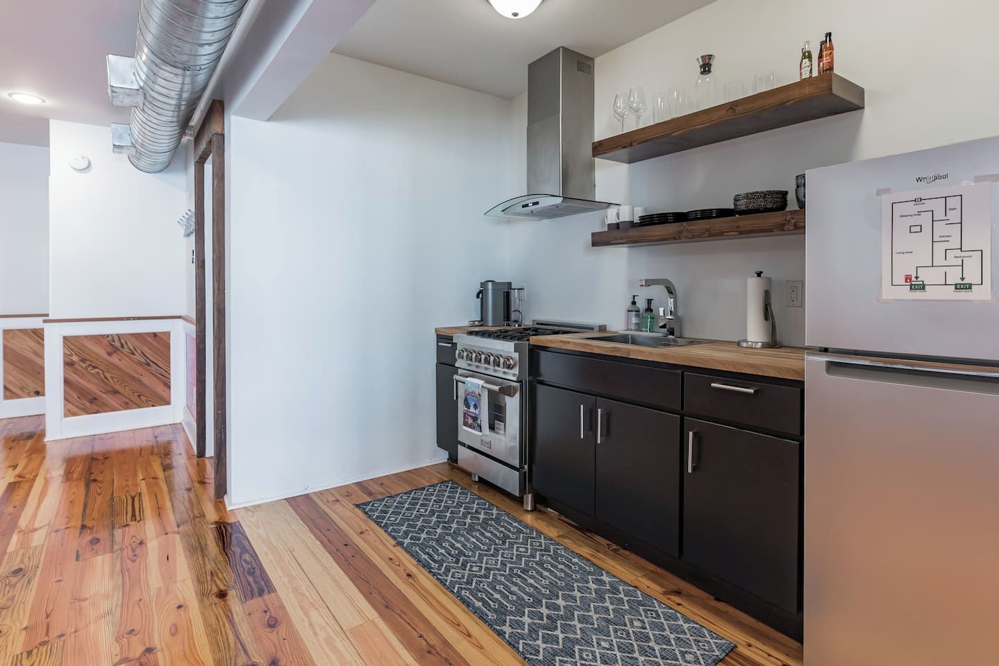 Una cocina moderna con horno empotrado, refrigerador de acero inoxidable y piso de madera.