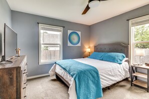 Une chambre à coucher avec un lit, une commode, des fenêtres et un ventilateur de plafond.