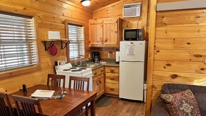 Une cuisine de taille réduite, dotée de meubles de rangement en bois, d’une cuisinière, d’un four à micro-ondes et d’un réfrigérateur.