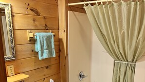 Une salle de bain aux murs lambrissés, équipée d’un lavabo, de toilettes et d’une baignoire.