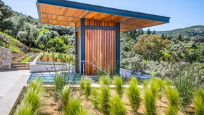 Un edificio moderno con fachada de madera, piscina y jardín ajardinado.
