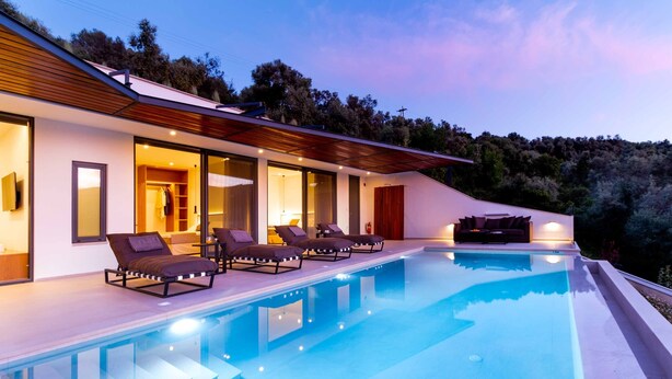 Una casa moderna con piscina, sillas de descanso y terraza de madera.