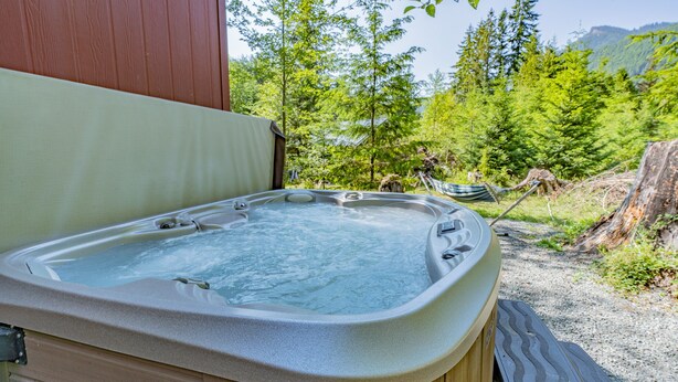 A hot tub with a wooden deck and a view of a forest and mountains. - Tiny Home@ Mt Rainier-Hot tub-AC (Ashford)
