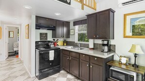 A kitchen with dark wood cabinets, a black stove, a microwave, and a sink. - Tiny Home@ Mt Rainier-Hot tub-AC (Ashford)