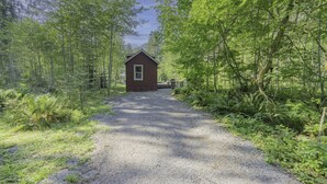 A gravel path leading to a small, single-story cabin surrounded by dense forest. - Tiny Home@ Mt Rainier-Hot tub-AC (Ashford)