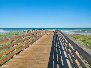 A wooden boardwalk leading to the beach with a clear view of the ocean.