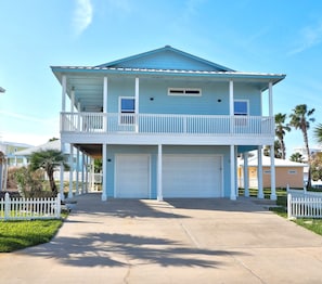 A two-story house with a balcony, a garage, and a white picket fence.