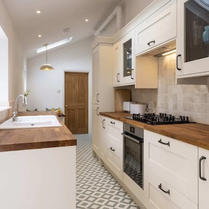 Una cocina moderna con armarios blancos, encimera de madera, horno empotrado y cocina a gas.