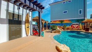 A pool area with a wooden deck, lounge chairs, and a mural of a beach scene. - Shared Heated Pool, 3rd Level Observation Deck, Golf Cart Included (Port Aransas)