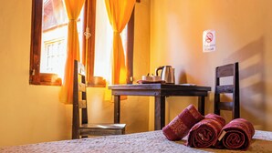 A room with a bed, a table with a kettle and cups, a chair, and a sign prohibiting smoking. - Residencial Los Pinos (Puerto Iguazú)