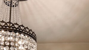 A chandelier with multiple crystal elements hanging from a dark metal frame. - The Chandelier House of Midtown - Near It All! (Memphis)