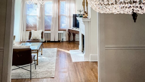 A spacious room with a chandelier, a fireplace, and a dining area with a table and chairs. - The Chandelier House of Midtown - Near It All! (Memphis)