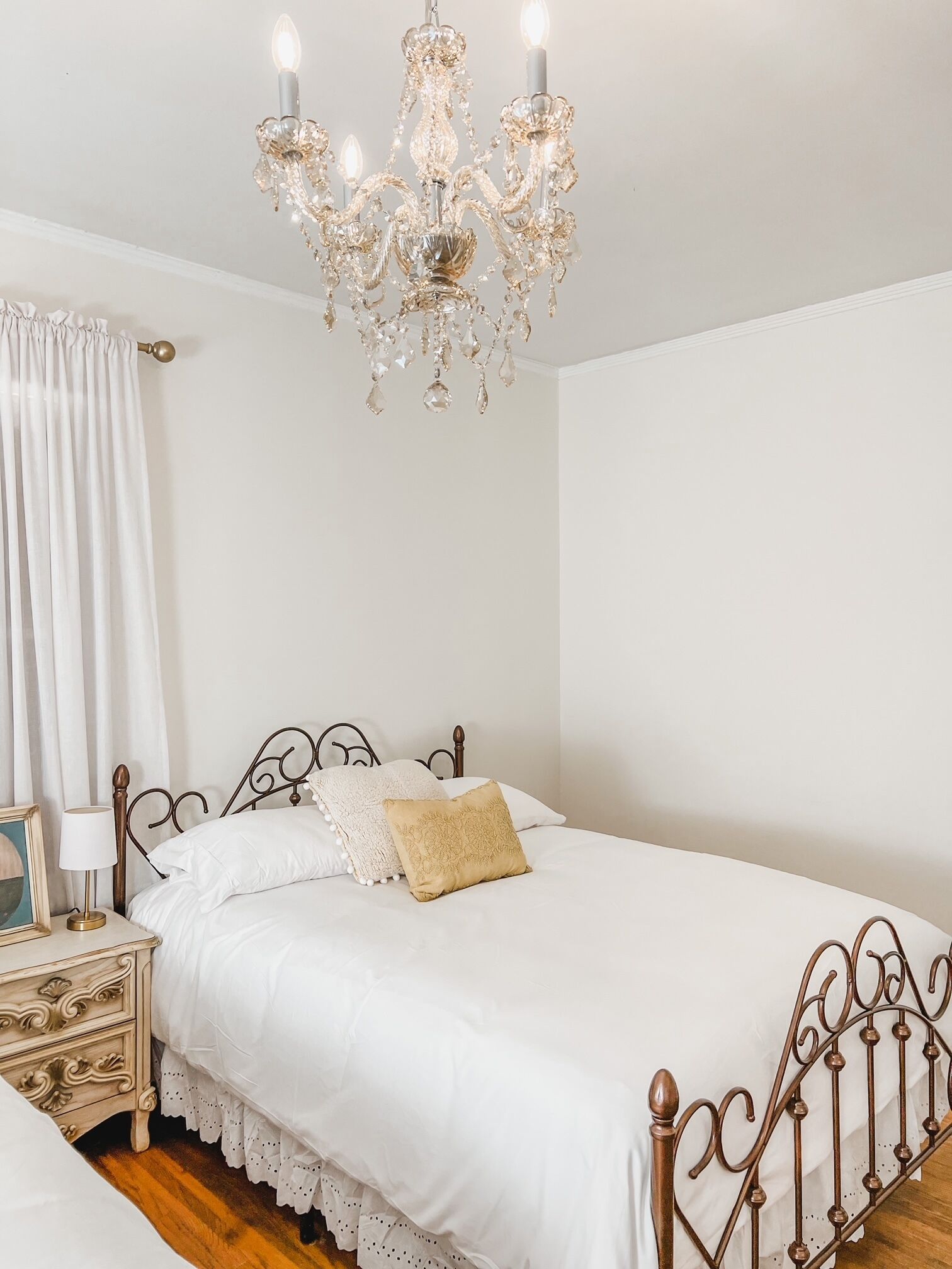 Une chambre à coucher avec un lit à baldaquin, un lustre, une table de chevet avec une lampe et une commode.