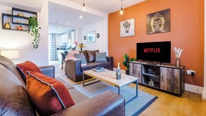 Een moderne woonkamer met een bank, salontafel en een televisie op een houten dressoir.