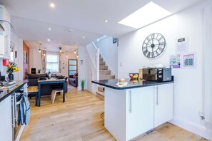 A modern kitchen with a central island, a dining area with a sofa and table, and a staircase leading to another level. - Stunning Home, Perfect for Groups, FREE Parking! (Chester)