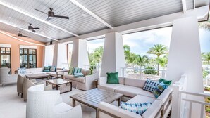 An outdoor lounge area with seating, ceiling fans, and large windows overlooking a landscaped area. - “Magical Memories Manor” - Awesome Movie and Game Rooms (Kissimmee)