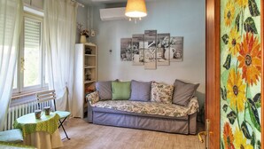 Ein gemütliches Wohnzimmer mit einer Couch, einem Tisch mit zwei Tassen, einer Heizung und einer Wand mit gerahmten Bildern.