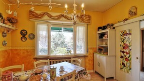 Ein Essbereich mit Tisch für vier Personen, einer Chandelier und einem fenster mit Vorhängen.