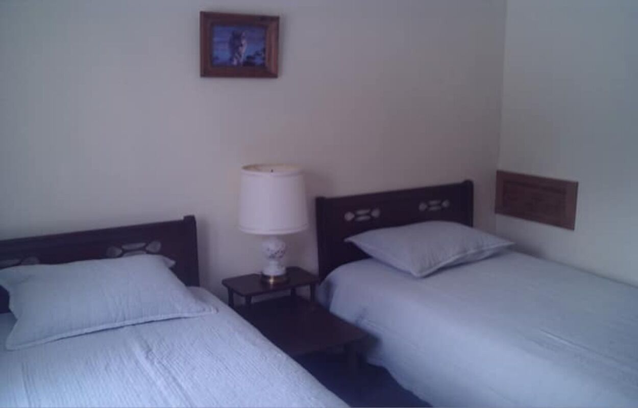 A room with two single beds, a bedside table with a lamp, and a framed picture on the wall.