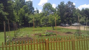 A fenced garden area with trees and a clear sky. - Trailside Townhouse in the center of Indian Lake (Indian Lake)