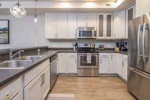 Una cocina moderna con armarios blancos, electrodomésticos de acero inoxidable y piso de madera.