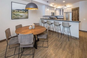 Una cocina moderna con armarios blancos, electrodomésticos de acero inoxidable y una mesa de comedor de madera con seis sillas.
