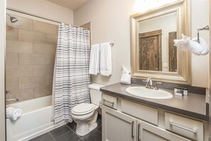 A bathroom with a bathtub, toilet, and a sink with a mirror above it.