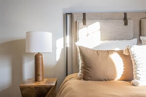 Un dormitorio con una cama, una mesita de noche de madera y una lámpara.