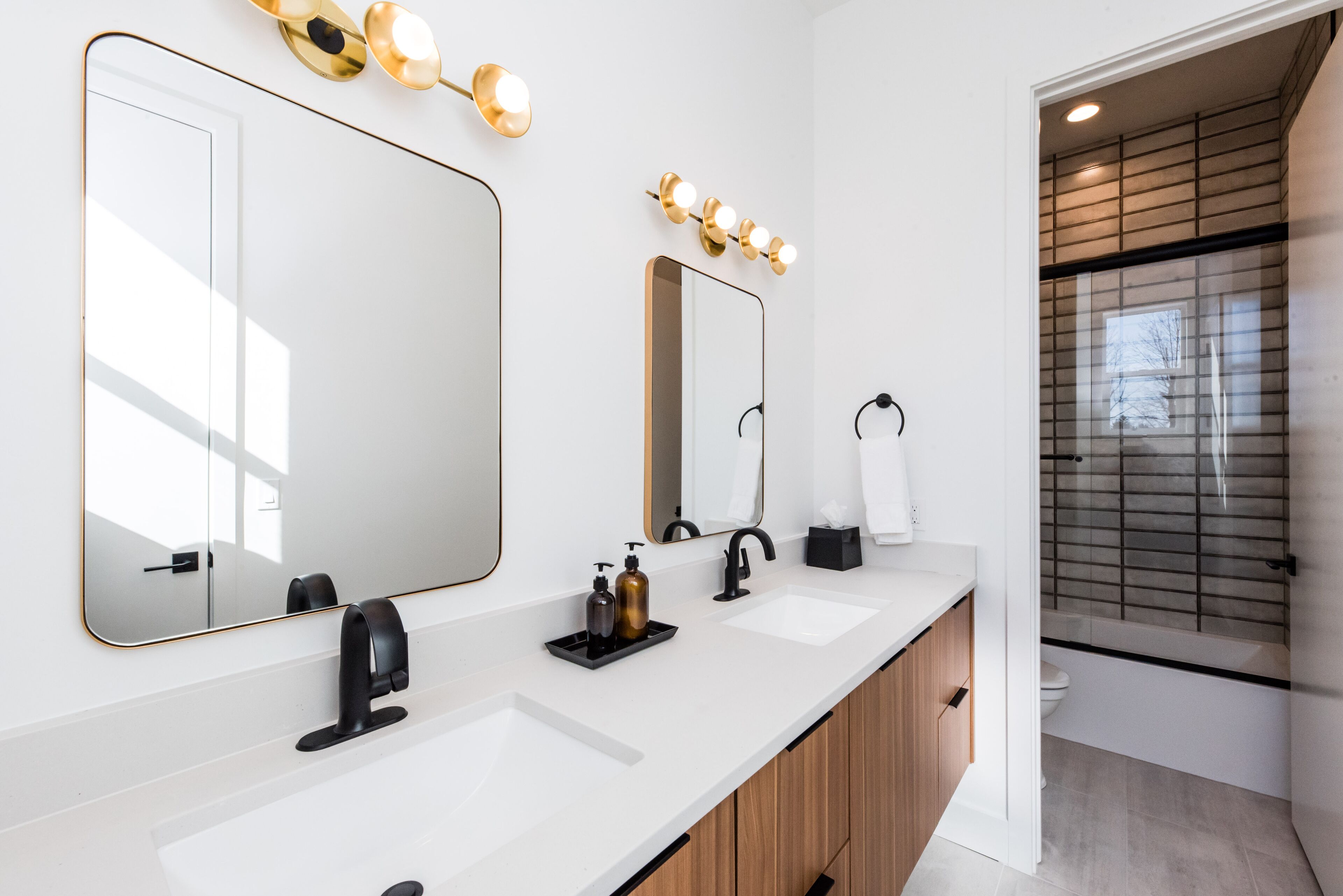 A modern bathroom with two sinks, a large mirror, and vanity lights.