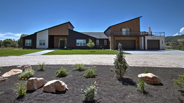 A modern two-story house with a driveway, a small lawn, and a gravel area with rocks and plants. - Luxury Home w/ Indoor Pool & Slide, Sports Court, Sleeps 40 (Garden City)