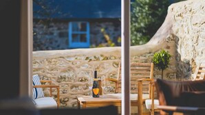 A stone wall with a blue door, wooden furniture, and a bottle of wine on a table.