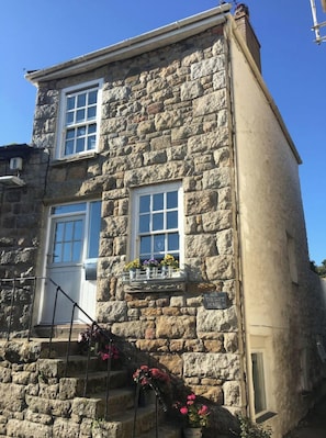 A stone building with two windows and a small balcony with flowers. - The Loft House - a beautiful 3 storey cottage (Mousehole)