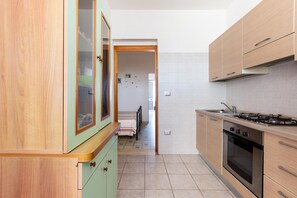 Une cuisine avec des meubles en bois, une cuisinière et un pare-feu en carreaux.