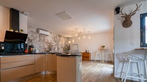 A modern kitchen with a central island, wooden flooring, and a rustic wall. - Le patio d'Oscar (Servigny-lès-Sainte-Barbe)