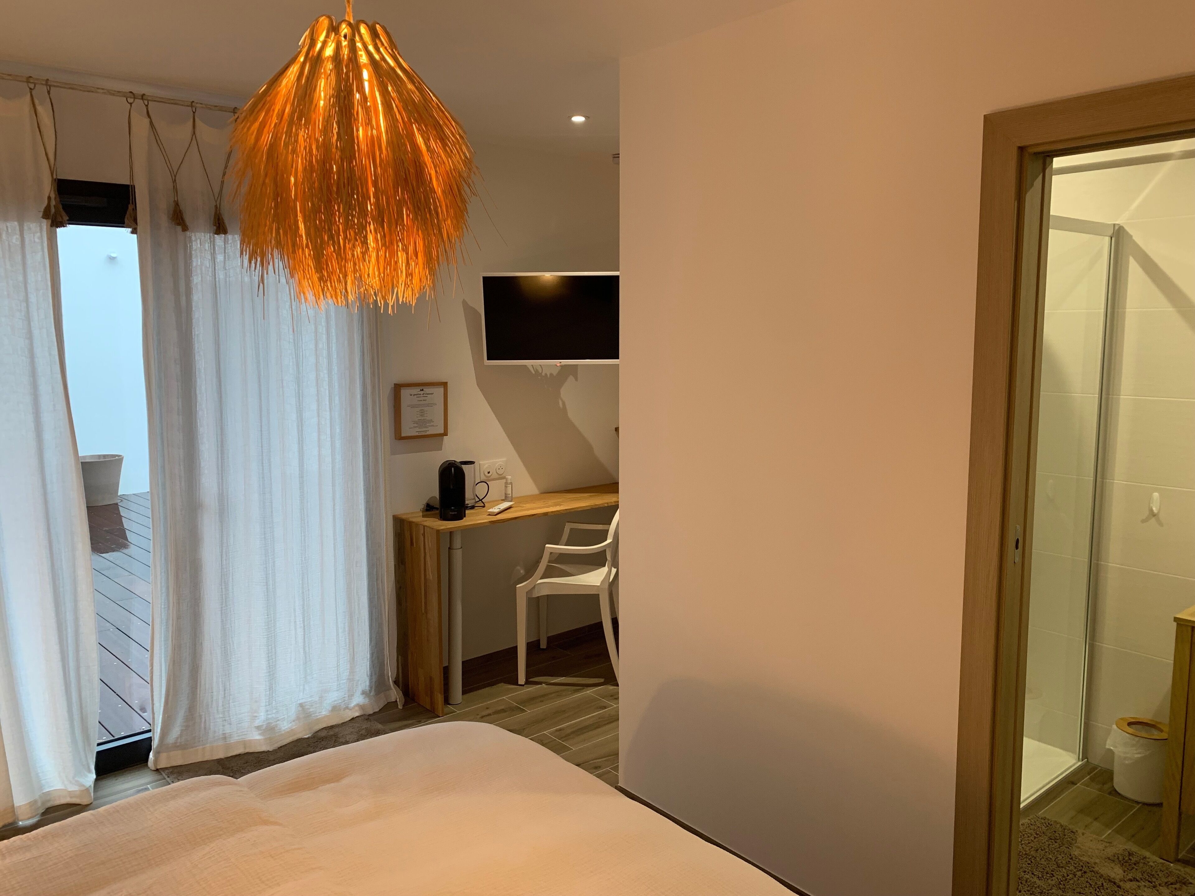 Une chambre moderne comprenant un lit, un bureau avec une chaise, une télévision et un espace douche.