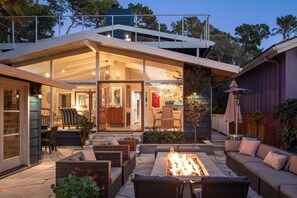 A modern house with a spacious patio, outdoor seating, and a fire pit.