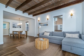 Relax in this spacious living area with a large sofa, dining space, and natural light pouring in through the large window.