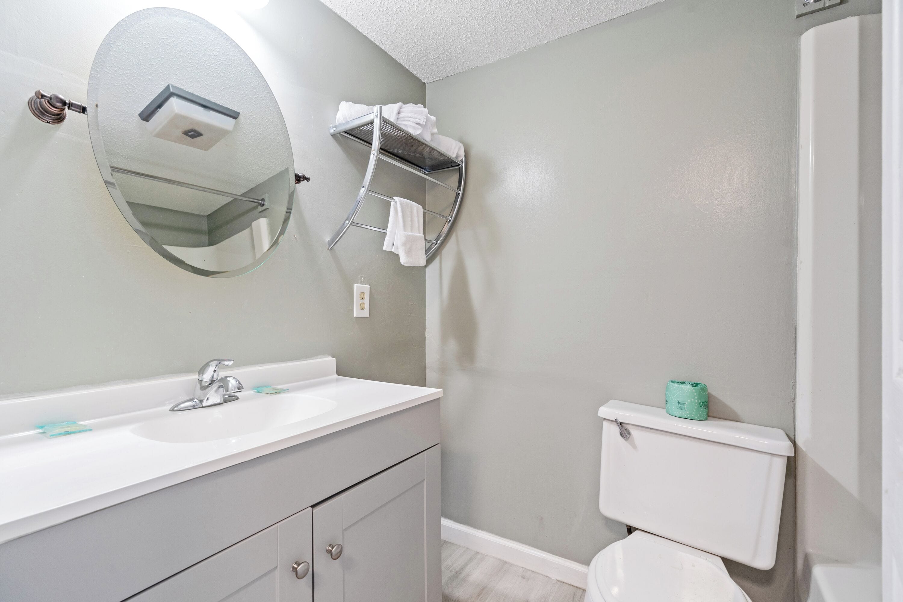 A bathroom with a white sink, a mirror, a towel rack, and a toilet.