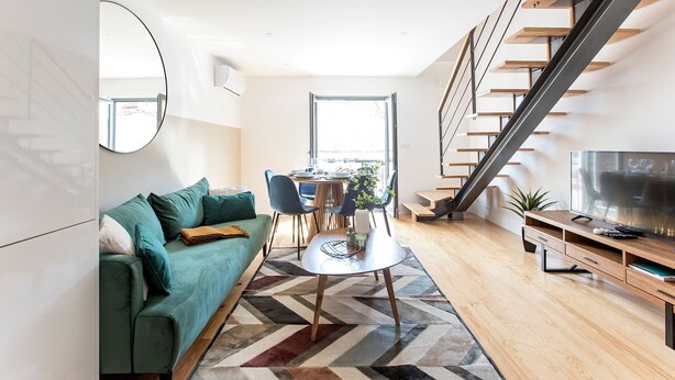 En moderne stue med en grøn sofa, et spisebord og en trappe.