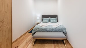 Une petite chambre à coucher, bien rangée, avec un lit, des tables de chevet et un banc.