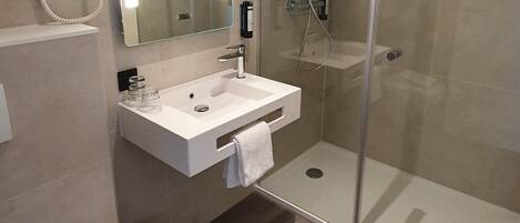 Une salle de bain moderne avec une douche à parois de verre, un lavabo blanc et un miroir au-dessus.