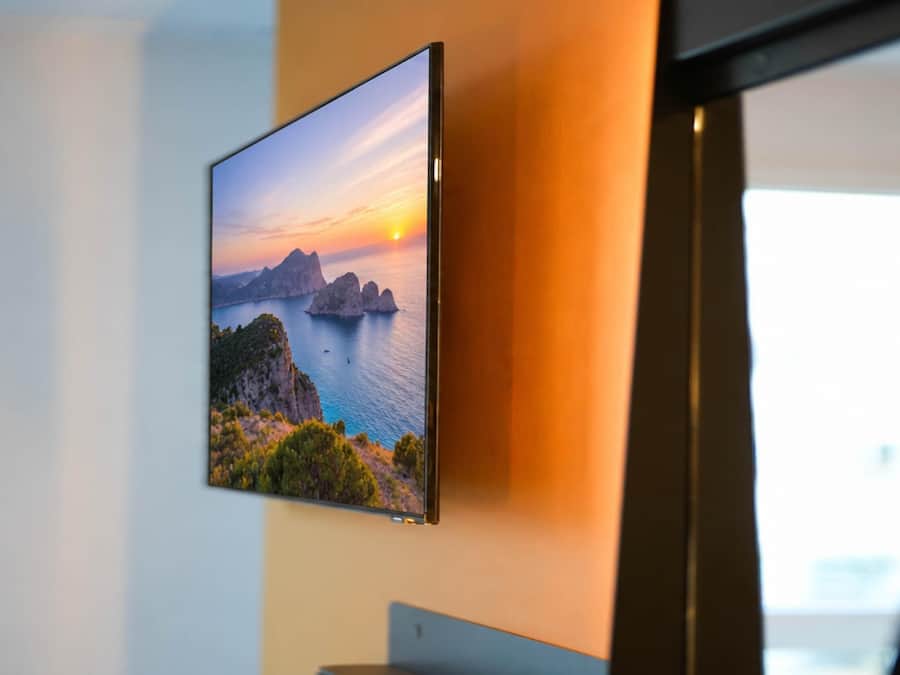 A flat-screen TV mounted on a wall displaying a scenic landscape.