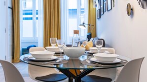 Une table à manger dressée avec de l’assiette blanche, des bols et des verres, entourée de chaises.