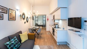 Un appartement moderne comprenant un coin repas, une kitchenette et un salon avec un canapé et des coussins décoratifs.