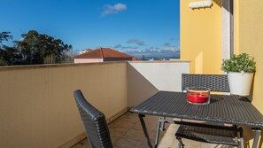 Un balcone con tavolo e sedie, una pianta in vaso e una candela rossa.