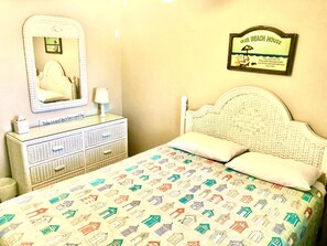A bedroom with a bed, a dresser, a mirror, and a wall sign.