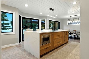 Een moderne keuken met een groot eiland, houten kastjes en een eethoek met tafel en stoelen.